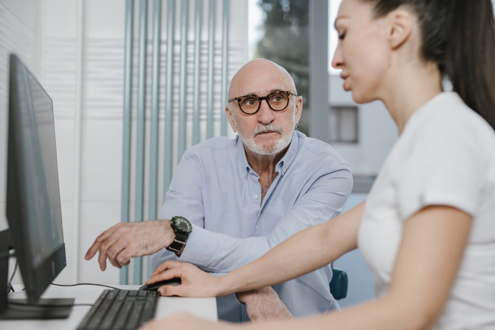 An older man talking with a clinician at a desk