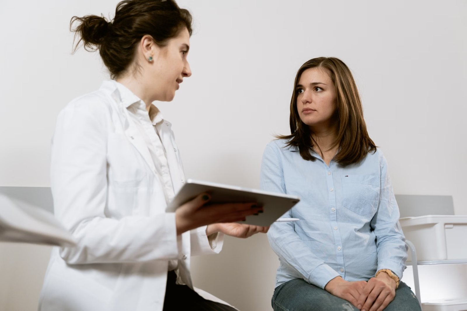 A clinician with a tablet talking with a woman in a consulting room