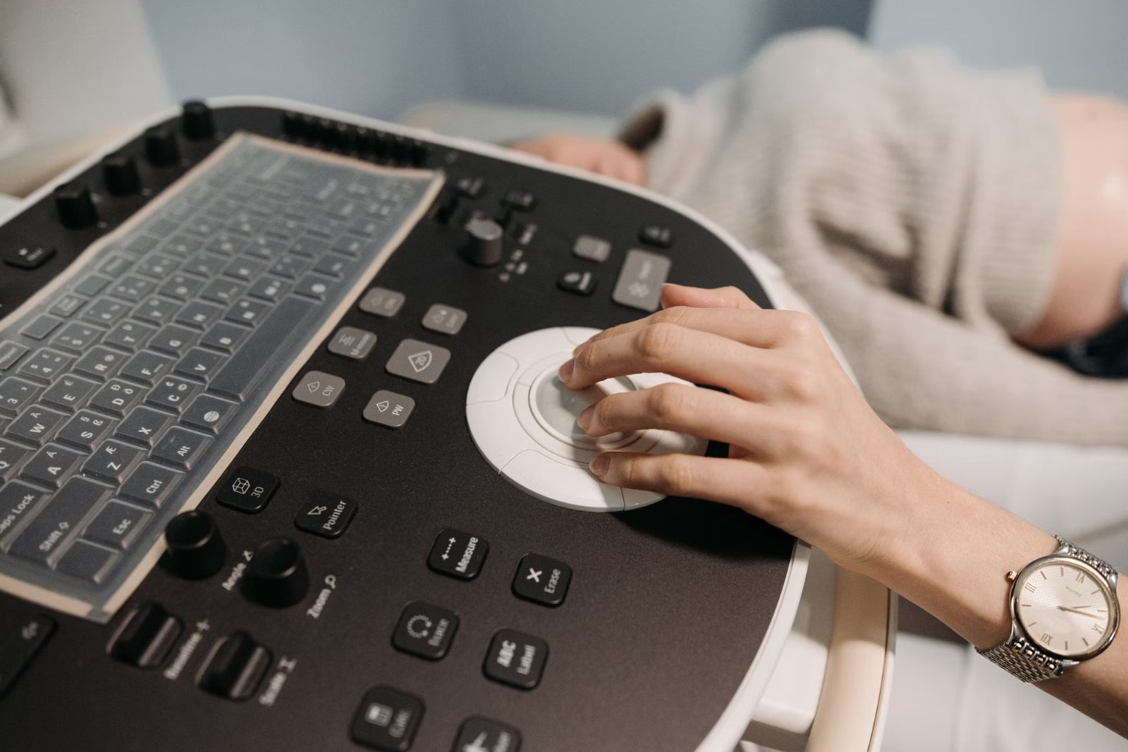 A hand on the control panel of an ultrasound machine