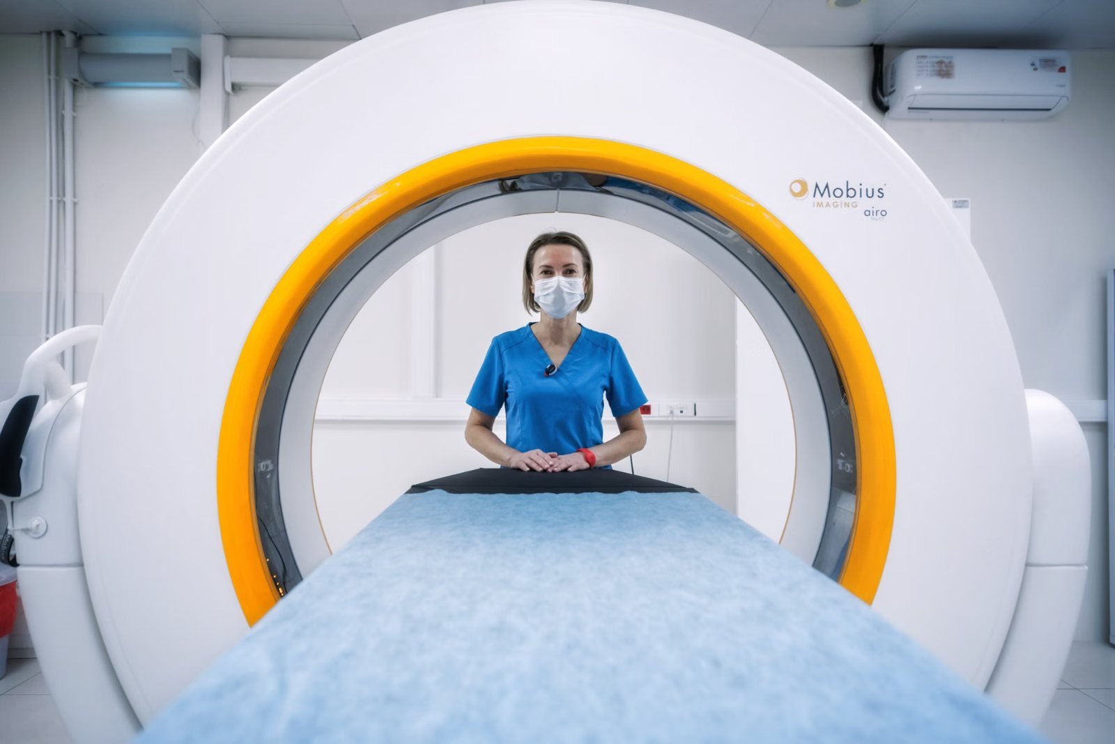 A radiographer standing inside the bore of a wide MRI scanner