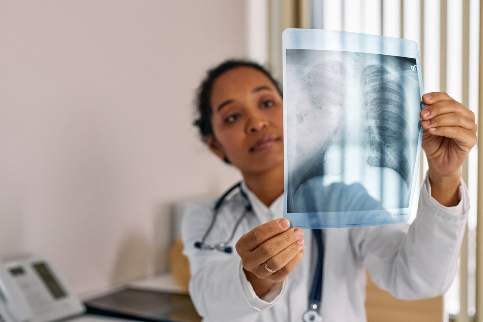 A doctor holding a chest X-ray in a consulting room