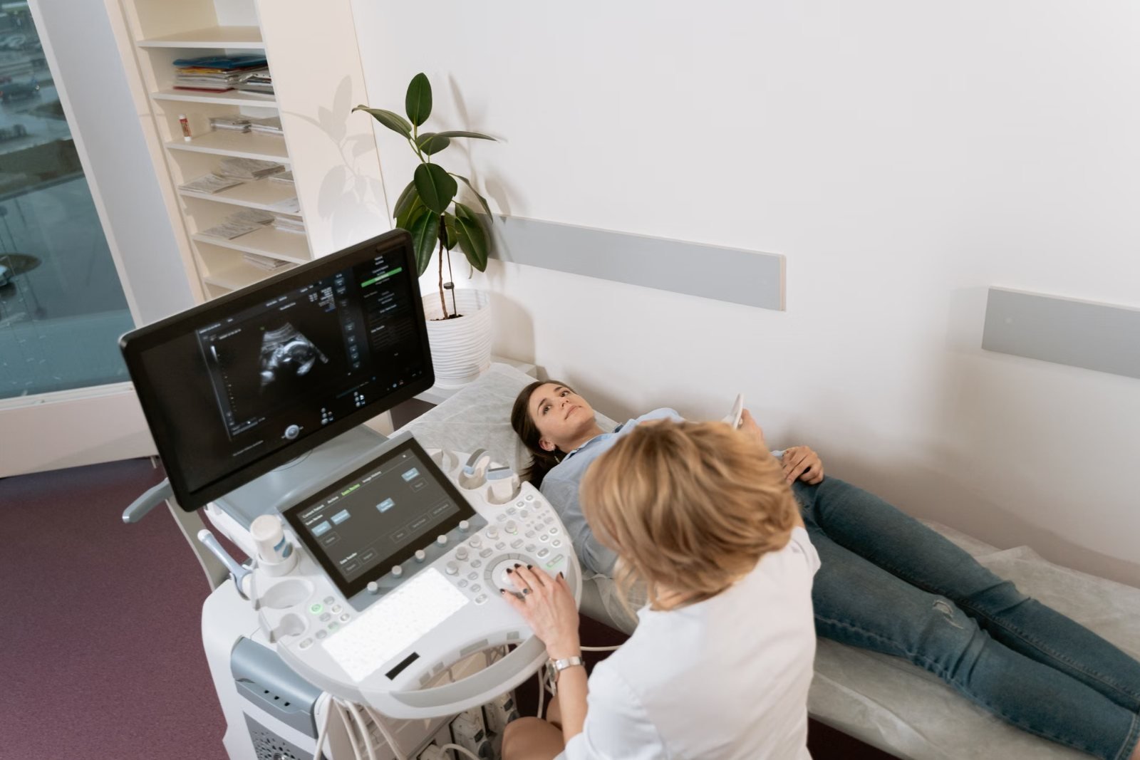 A sonographer with a patient beside an ultrasound machine