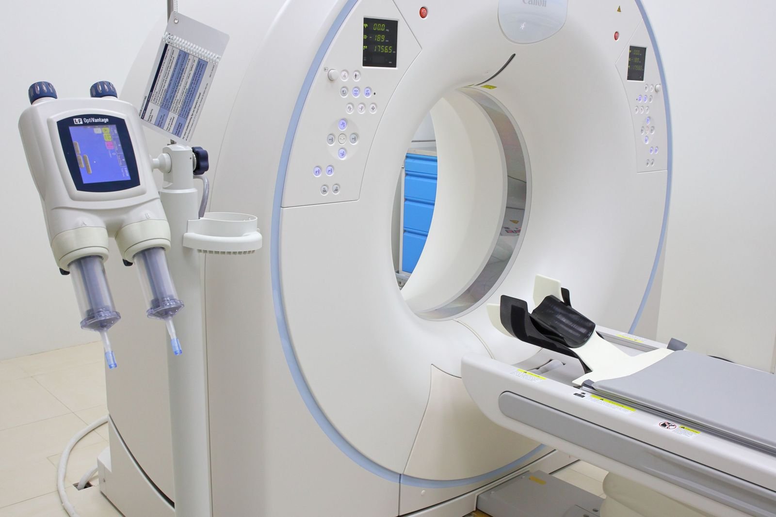 A CT scanner with a contrast injector beside it