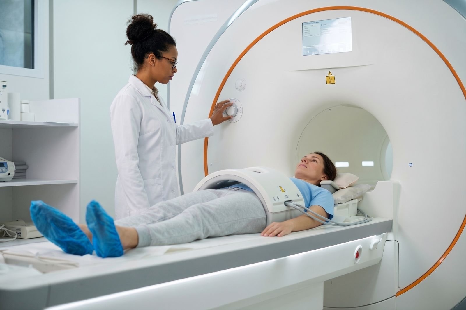 A radiographer positioning a patient with an abdominal coil for an MRI scan