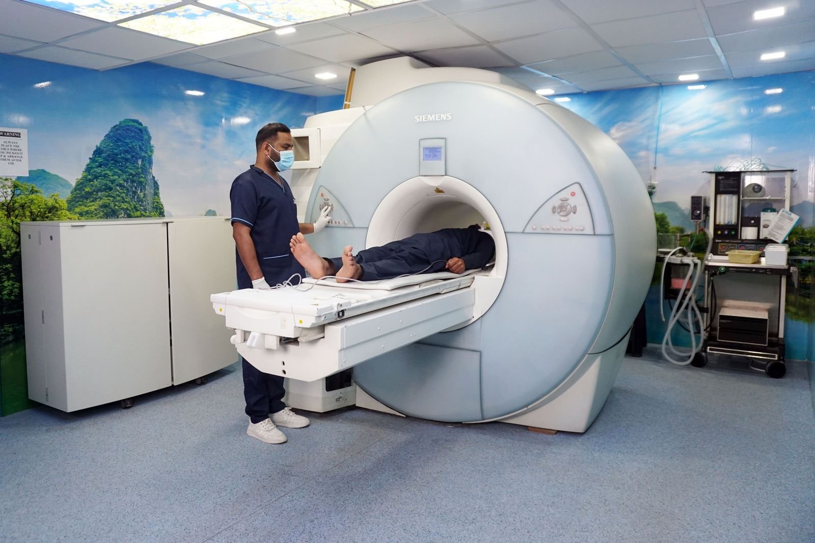 A radiographer with a patient on an MRI scanner in a bright room